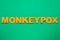 Word Monkeypox made of bright letters on green background, top view