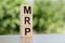The word MRP Abbreviation of Material requirements planning, built from wooden cubes outdoors on the background of nature