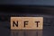 word NFT, non-fungible token made from wooden blocks on a laptop. The concept of earning on NFT