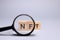 word NFT, non-fungible token through a magnifying glass. NFT analysis concept