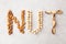 Word NUTS spelled with various nuts on stona background. Assorted mixed nuts