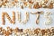 Word NUTS spelled with various nuts on stona background. Assorted mixed nuts