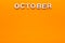 Word October on orange background