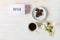 Word OPEN displayed on lightbox, coffee cup, chocolate on plate and vase with blossoms on wooden table