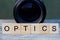 Word optics made of wooden letters and black lens