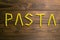 The word pasta is made from pasta Pene Lisce on a wooden table. Top views