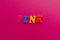 Word `pink` from plastic colored magnet letters on pink paper ba