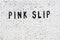 Word pink slip painted on white brick wall