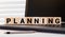 word planning made with letters on wooden blocks on desk with different color graphs and diagram in room closeup