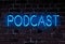 Word PODCAST in glowing neon letters on rough brick wal