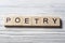 Word POETRY on wood abc cubes at wooden background.