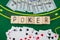 The word poker on wooden cubes, poker chips with playing cards on the green casino table