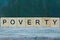 The word poverty from wooden letters on a gray table