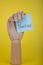 The word Prioritize on a blue posted note held by a fake wooden hand on yellow background