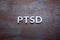 The word PTSD laid with silver metal letters on flat rusted steel sheet background in straight perspective