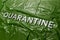 The word quarantine laid with silver letters on green crumpled plastic film background in diagonal perspective