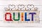 The word quilt sewn from colorful square and triangle pieces of fabric