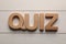 Word Quiz made with wooden letters on white table, flat lay