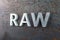 The word raw laid with silver metal letters on hot rolled steel sheet surface