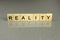 Word reality is made up of square wooden letters on a gray background