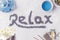 The word relax from lavender on a white background near to the flowers of daisies, aroma sticks and blue tea in a teapot and mug.