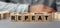 The word REPEAT made from wooden cubes. Selective focus