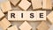 Word rise with black letters on wooden blocks and details