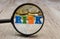 The word `risk` laid out of letters through a magnifying glass / coins on a wooden background. The concept of economic risk.