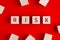 The word risk written on wooden blocks on red background.