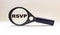 The word RSVP is written on the lens of a magnifier