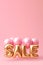 Word SALE made of golden inflatable balloons on pink background. Helium balloons gold foil forming word sale. Discount and