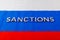 the word sanctions laid with silver metal letters on russian tricolor flag