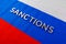 the word sanctions laid with silver metal letters on russian tricolor flag in diagonal perspective