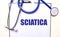 The word SCIATICA is written on a white sheet near the stethoscope. Medical concept