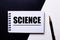 The word SCIENCE written in red on a black and white background near the pen
