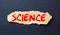 The word SCIENCE written in red on a black and white background near the pen