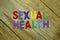 Word SEXUAL HEALTH colorful wooden alphabet letters set on wooden background. Healthcare and medical concept