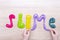 The word slime made from multi-colored slimes on a wooden table. Slime text made of colored slime on a wooden surface. Child`s