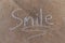The word Smile written with sidewalk chalk on gray concrete
