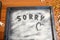 Word Sorry is written on a baking tray sprinkled with icing sugar or flour