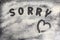 word Sorry is written on a baking tray sprinkled with icing sugar or flour