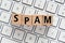 The word SPAM made of wooden letters located on a white computer keyboard. Business concept