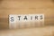 The word Stairs is written in cubic letters on a wooden background