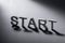 Word START written with white plastic letters on a gray background