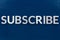 the word subscribe laid with aluminium letters on blue paint board background