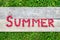 Word Summer made from raspberries on wooden and grass background