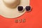 Word Sun from wooden letters. Sun glasses and hat. Live coral background. Travel concept