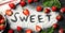 Word Sweet made sugar, and strawberry on wooden background, top view. Summer berry