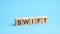 word swift made with wood building blocks. text is written in black letters, blue background