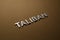 the word taliban laid with silver metal letters on rough tan khaki canvas fabric